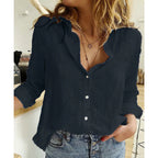 Front view of a navy linen button-front blouse paired with denim jeans in a kitchen setting