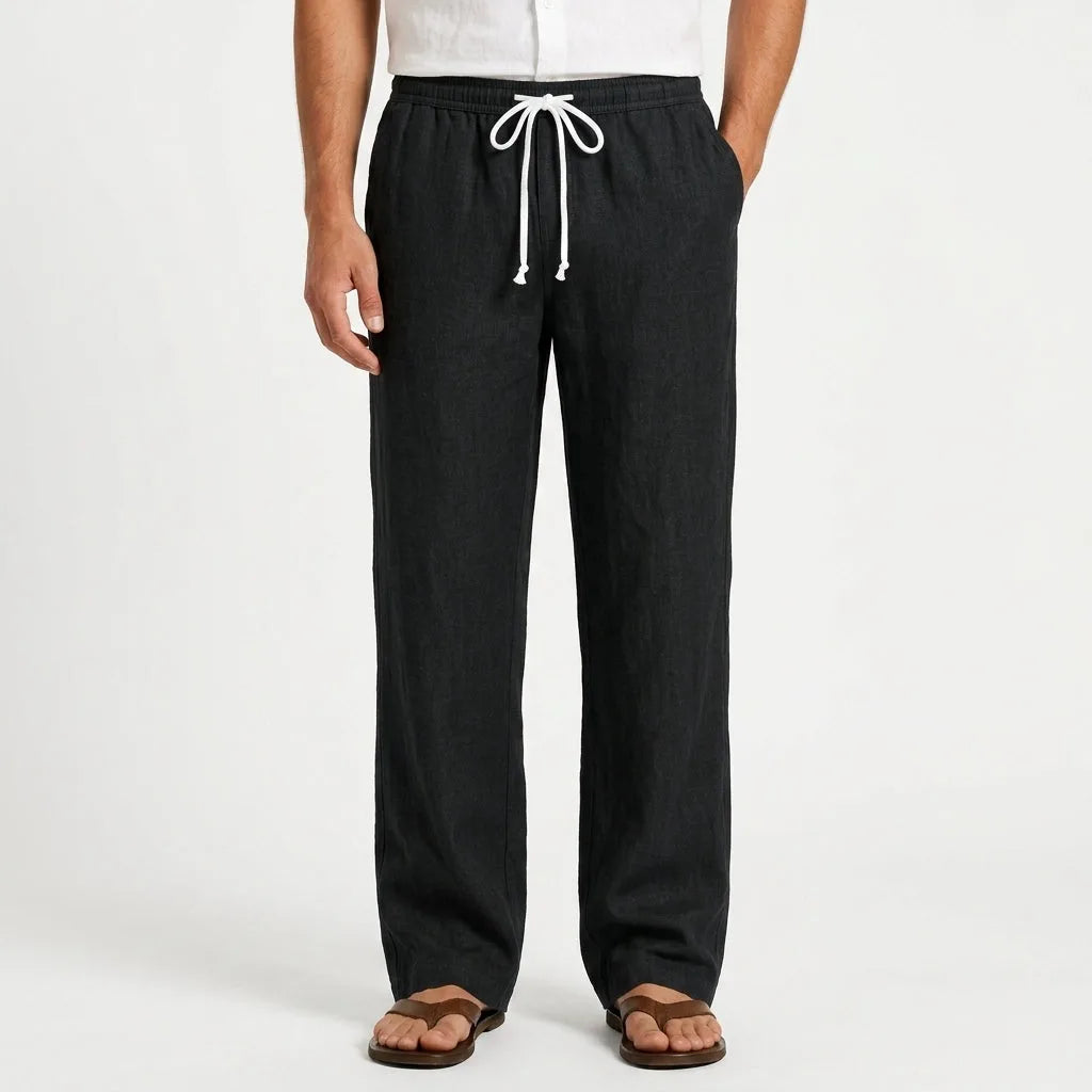 Front view of black linen drawstring trousers worn with a white shirt and brown leather sandals