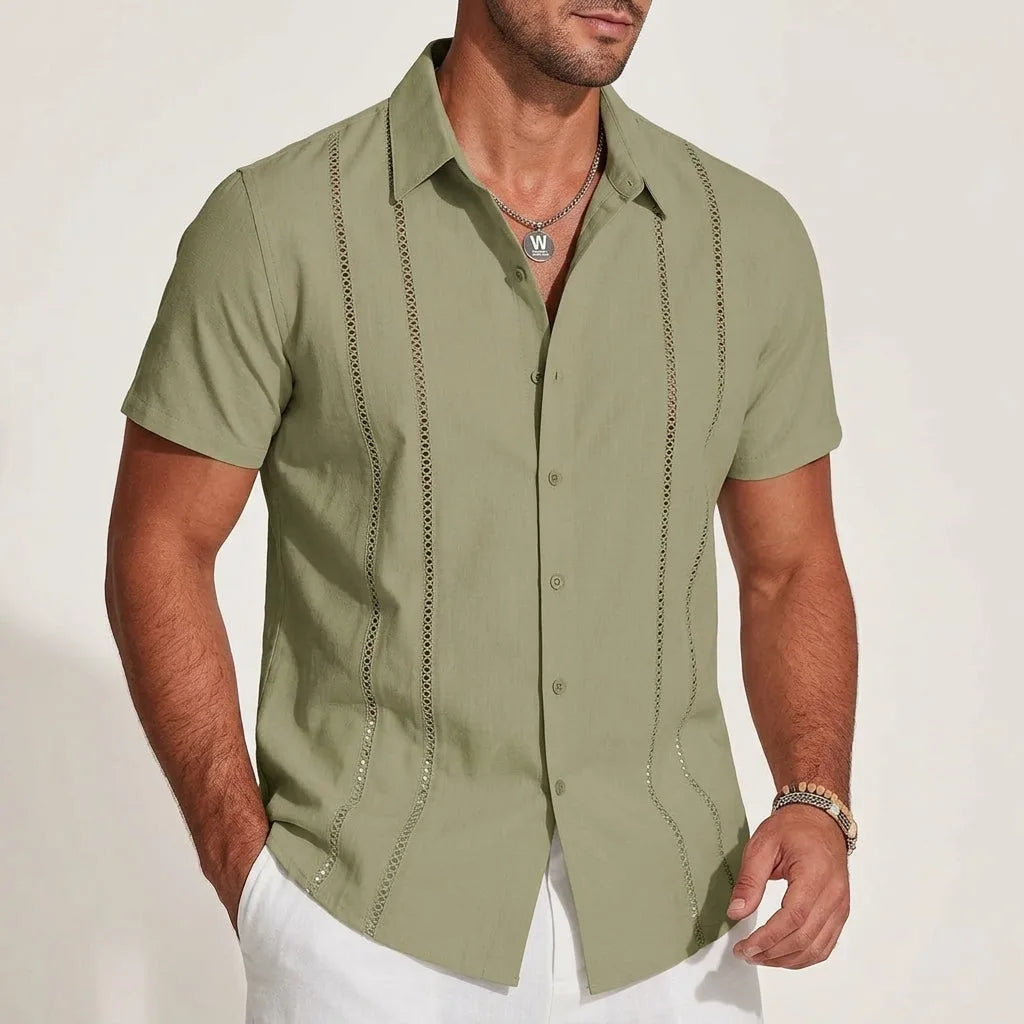 Sage green short-sleeve guayabera shirt styled with white trousers, showing the classic camp collar