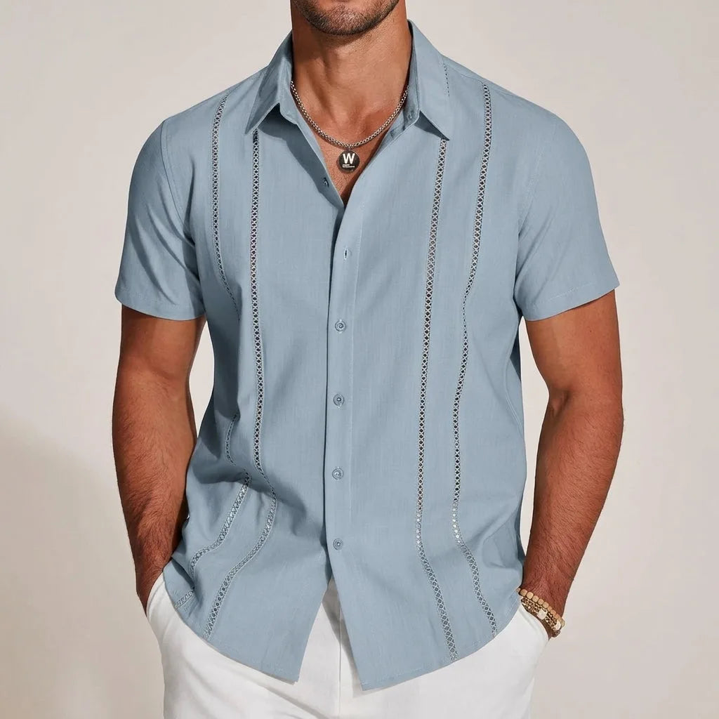 Dusty blue guayabera shirt with lace-panel detailing worn open-collar over white trousers