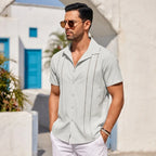 Light grey guayabera shirt worn outdoors against a white Mediterranean-style wall with blue door