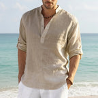 Close-up of a man in a beige linen Henley shirt with button placket, worn open-neck by the sea