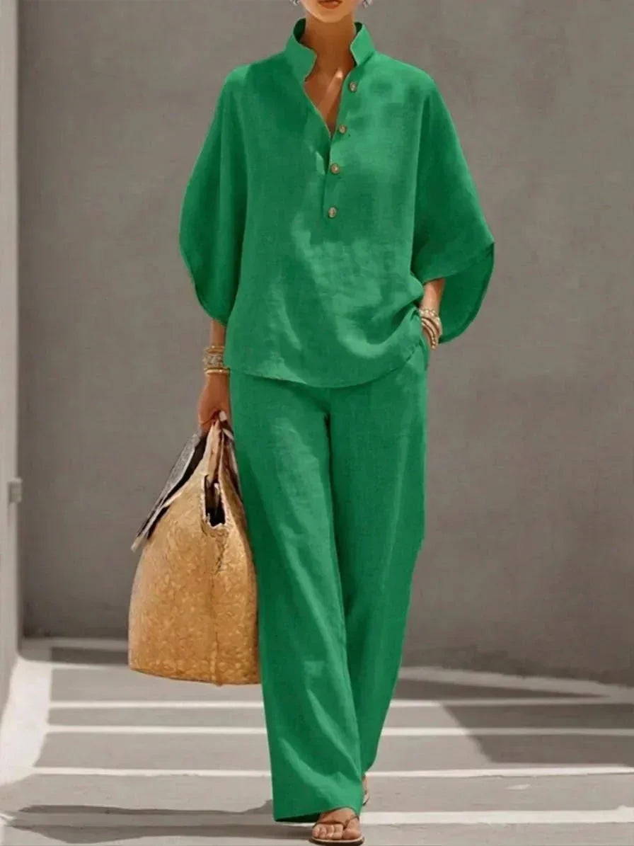 Green colourway of the batwing-sleeve top and wide-leg pants set, styled with gold bangles and a woven straw handbag.