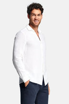 Side view of man in white linen long-sleeve shirt with spread collar, worn untucked over navy chinos