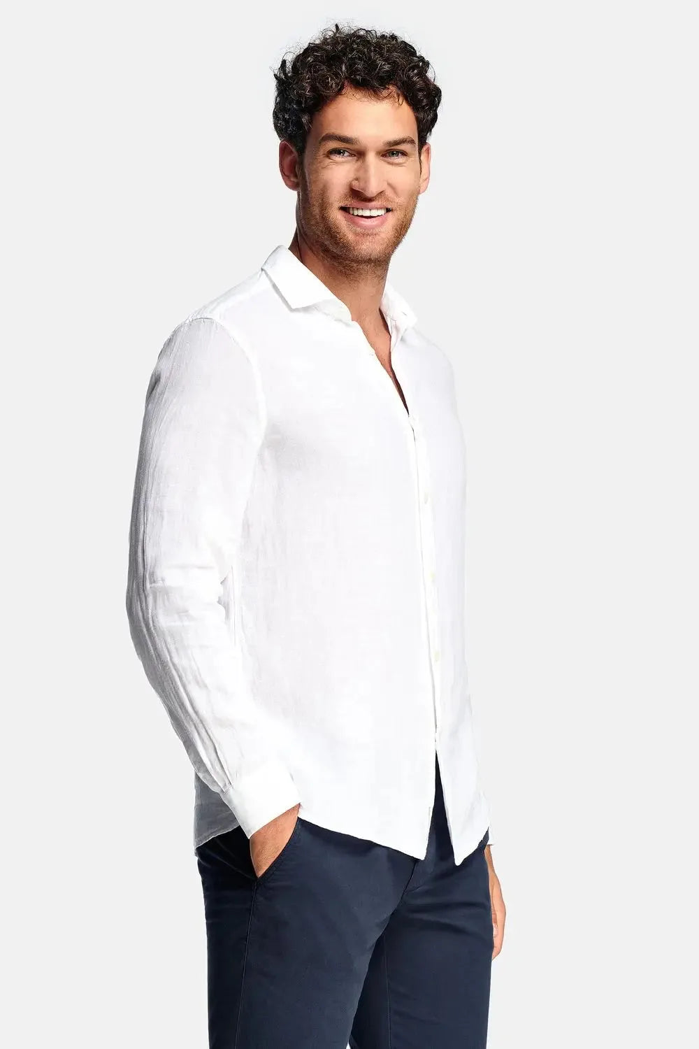 Side view of man in white linen long-sleeve shirt with spread collar, worn untucked over navy chinos