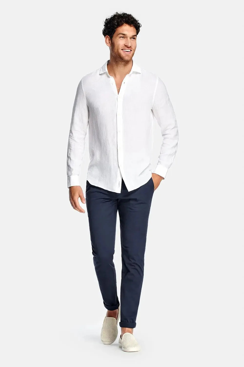 Full-length front view of model wearing the white linen shirt with navy chinos and cream slip-on sneakers