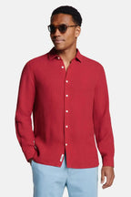 Front view of man wearing a burgundy red long-sleeve linen shirt fully buttoned with white buttons