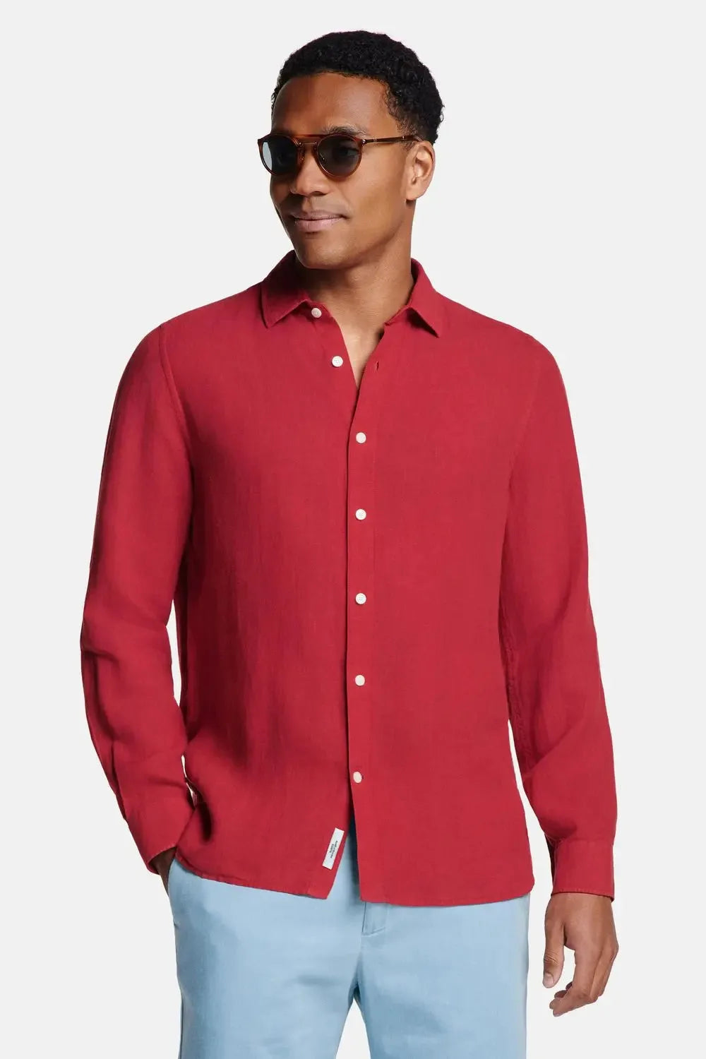 Front view of man wearing a burgundy red long-sleeve linen shirt fully buttoned with white buttons