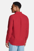 Back view of man in burgundy linen shirt paired with light blue trousers