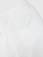 Close-up of back patch pocket with button closure on white linen trousers