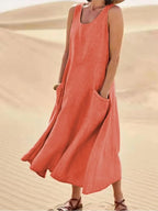 Orange linen sleeveless midi dress with front pockets, worn outdoors against desert dunes