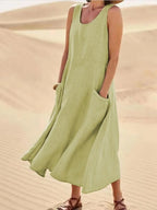 Light olive green linen sleeveless midi dress with A-line skirt, worn with sandals in sand