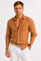 Rust brown linen shirt with natural fabric texture, long sleeves and point collar, worn open at the chest.