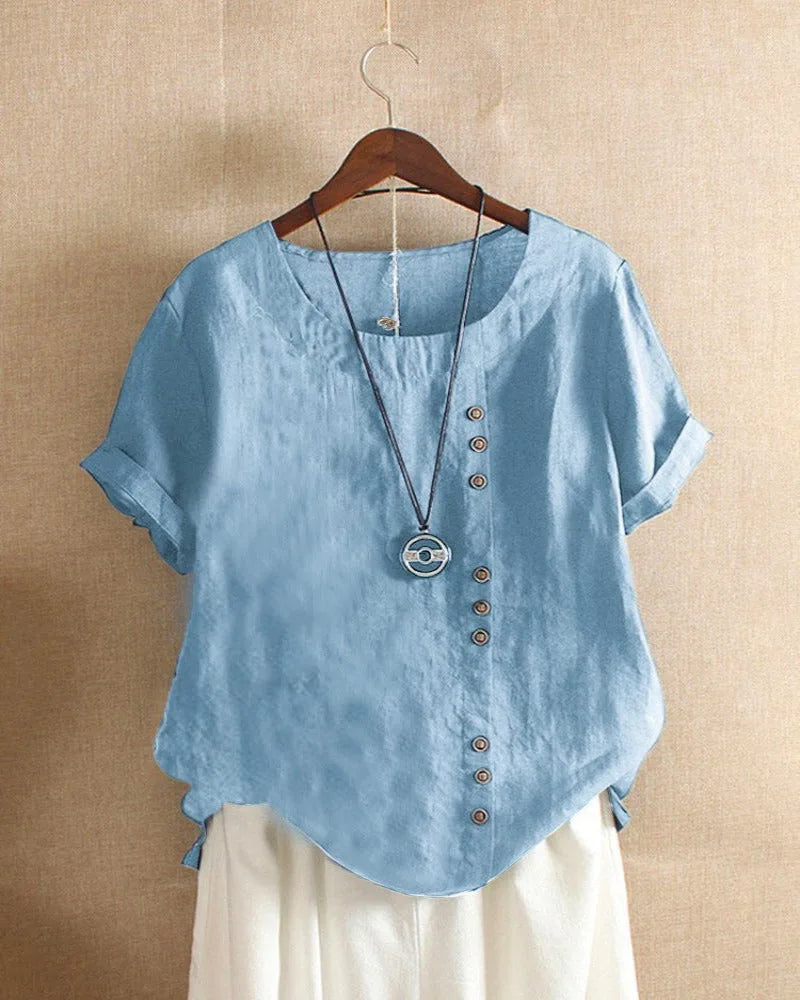 Light blue linen blouse on a wooden hanger, showing the curved hem and relaxed, breathable silhouette