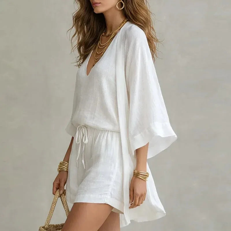 Side profile showing the flowing drape of the white linen kimono layered over the matching top and shorts