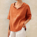 Orange linen collared V-neck blouse with rolled half sleeves and button cuff detail, close front view