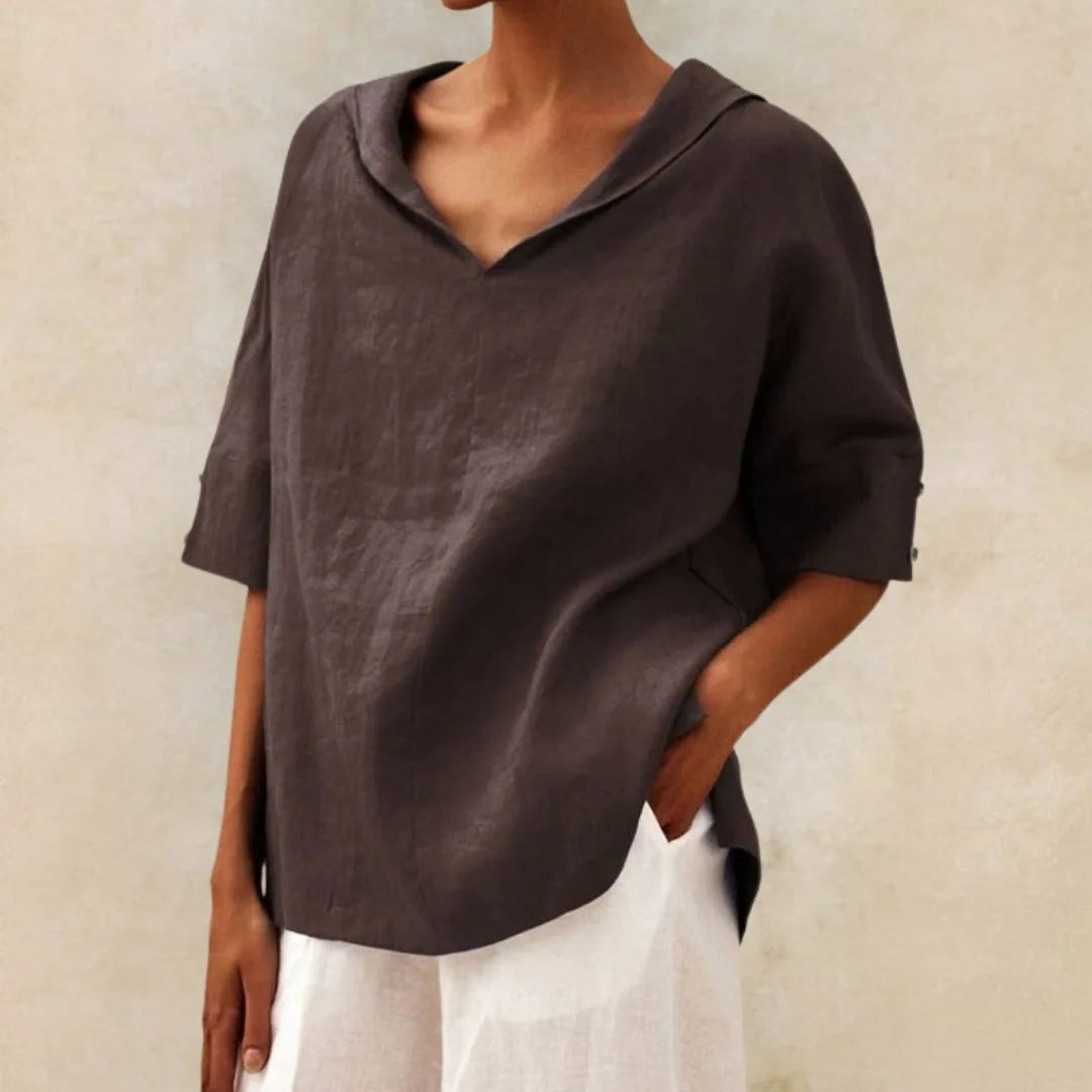 Charcoal brown linen collared top with elbow length sleeves and a curved hemline over white trousers
