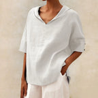 Light grey linen V-neck top with button cuff sleeve detail, worn loosely over white wide leg trousers