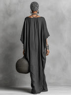 Back view of the dark grey batwing sleeve maxi dress showing its flowing, loose drape from shoulders to floor length hem