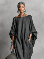 Front portrait view of the dark grey maxi dress with round neckline, worn with a printed headscarf and layered necklaces