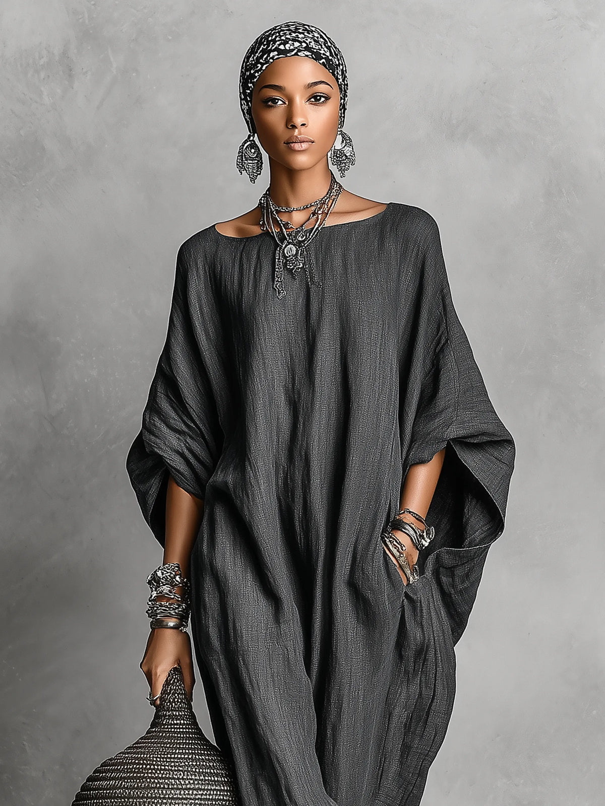 Front portrait view of the dark grey maxi dress with round neckline, worn with a printed headscarf and layered necklaces