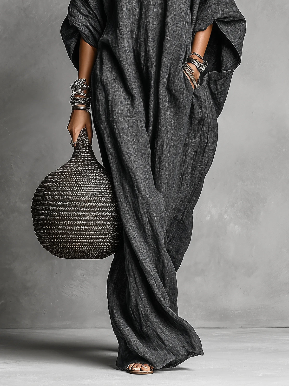 Detail shot of the dress's side pocket and batwing sleeve drape, with the model's hand resting inside the pocket