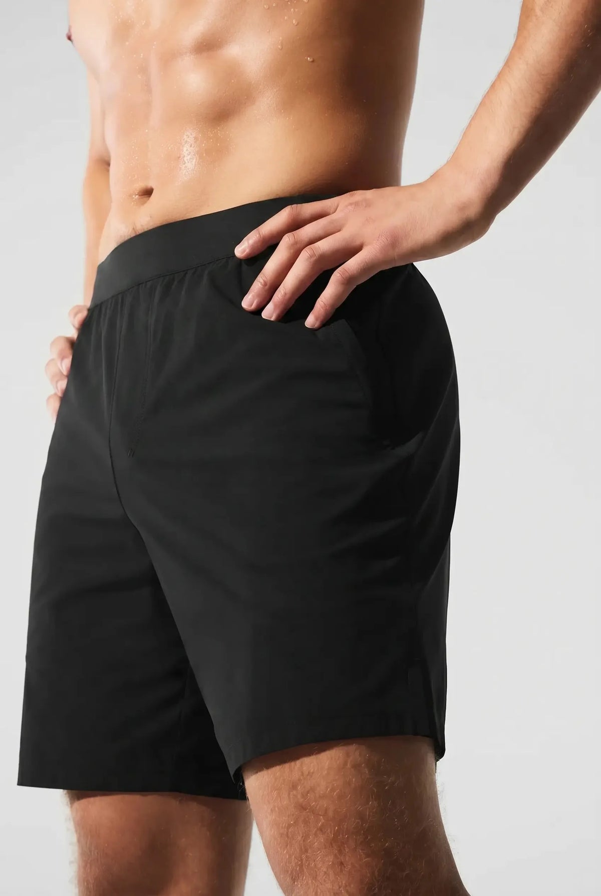 Close-up side view of a man wearing black active shorts with an elastic waistband and side pocket