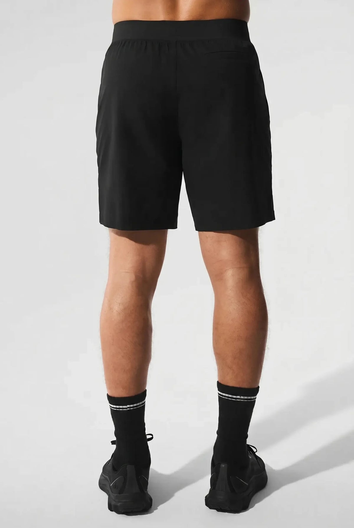 Back view of black active shorts paired with black sneakers and crew socks, showing fit through the seat