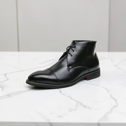 Side view of a black leather chukka boot with cap toe and lace-up front, shown on a marble surface
