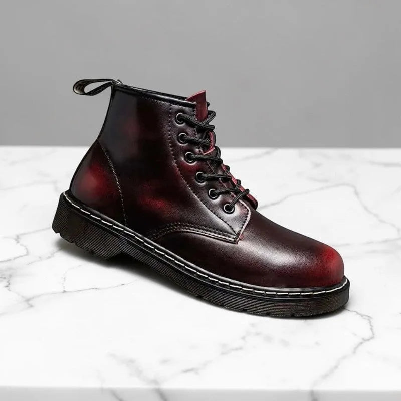 Side profile of a burgundy leather lace-up combat boot with black laces and a rounded toe, on a marble surface.