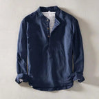 Navy blue linen shirt laid flat on concrete, close view of stand collar and rolled cuffs