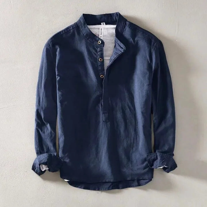 Navy blue linen shirt laid flat on concrete, close view of stand collar and rolled cuffs