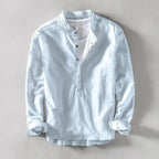 Sky blue collarless linen shirt flat lay with visible stitching and rolled sleeve hems