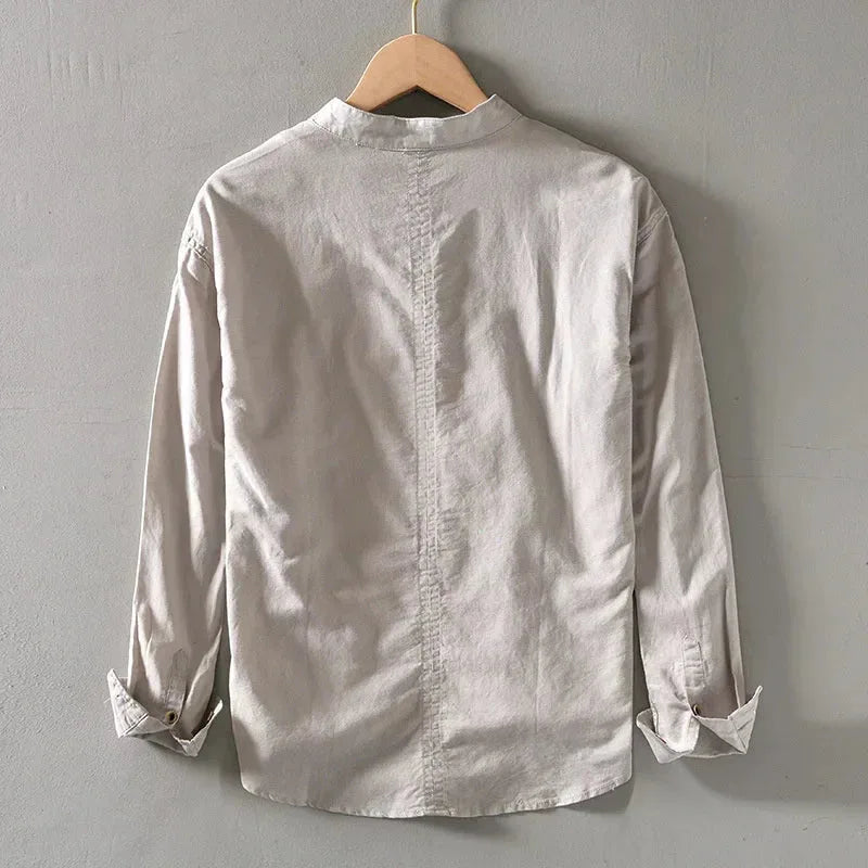 Beige linen shirt on wooden hanger, back view showing centre seam and relaxed shoulders
