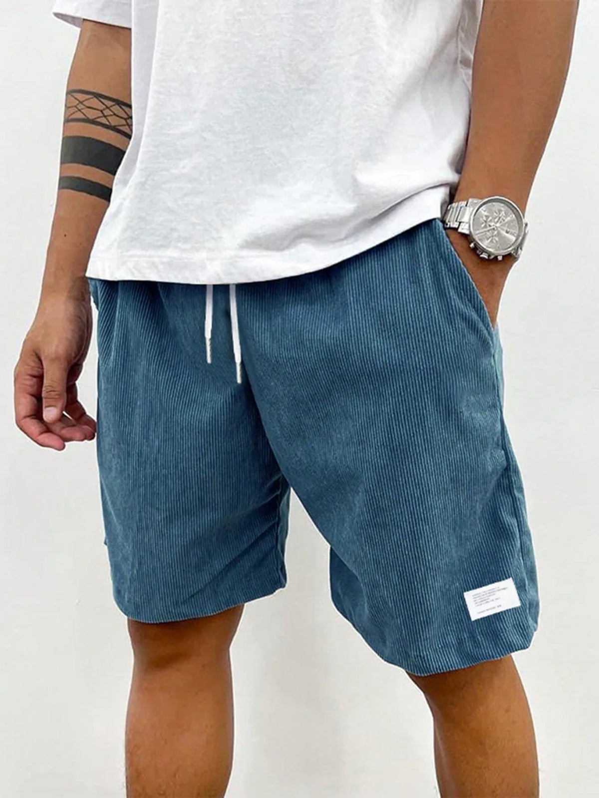 Front angle of teal blue corduroy shorts with hand in pocket and drawstring detail