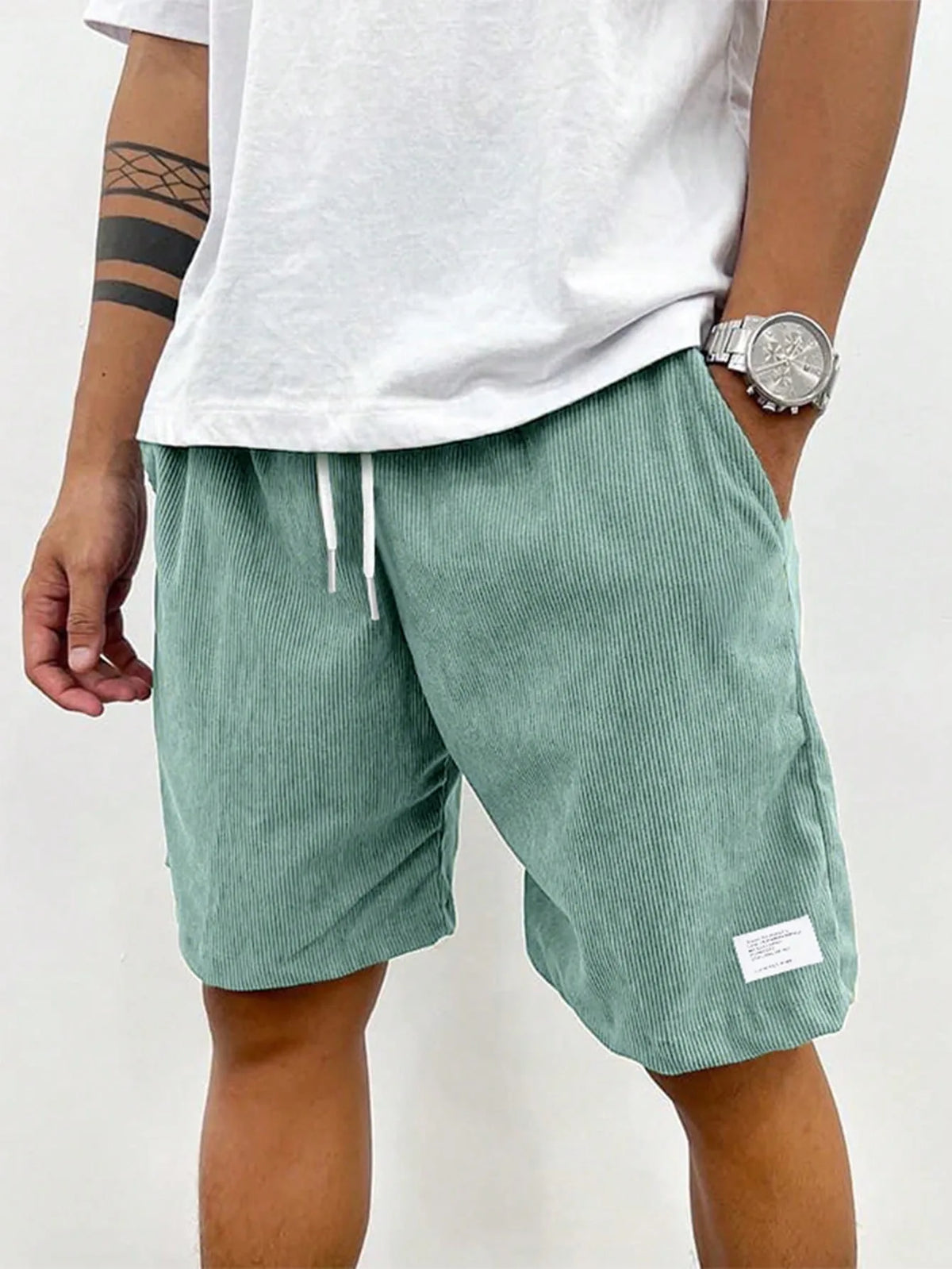 Front view of sage green ribbed corduroy shorts with white drawstring and side pocket