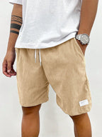 Front view of beige ribbed corduroy shorts worn with white t-shirt and silver watch