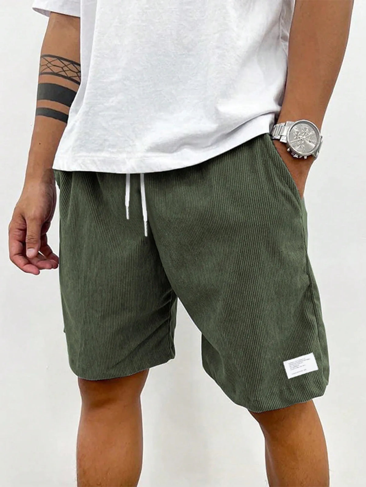 Close-up of teal blue corduroy shorts showing woven fabric label near hem