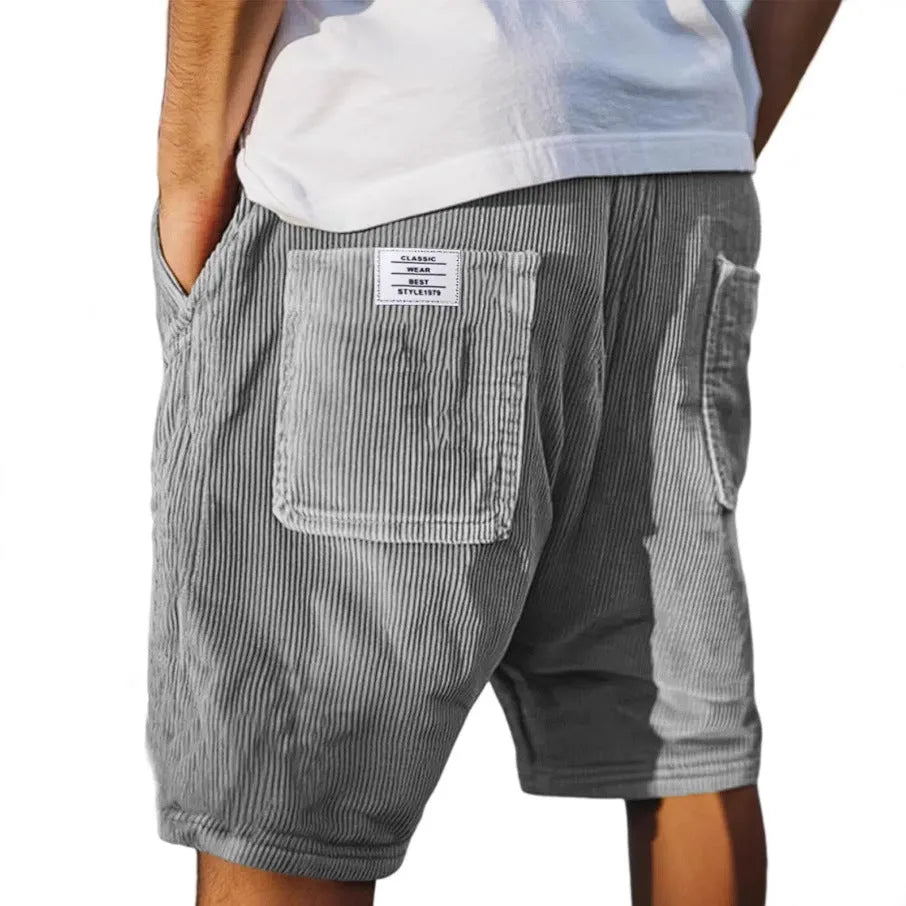 Back view of grey corduroy shorts with patch pocket and side pocket, worn with a white t-shirt