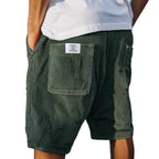 Dark green corduroy shorts worn with hands in pockets, showing the ribbed texture and loose silhouette