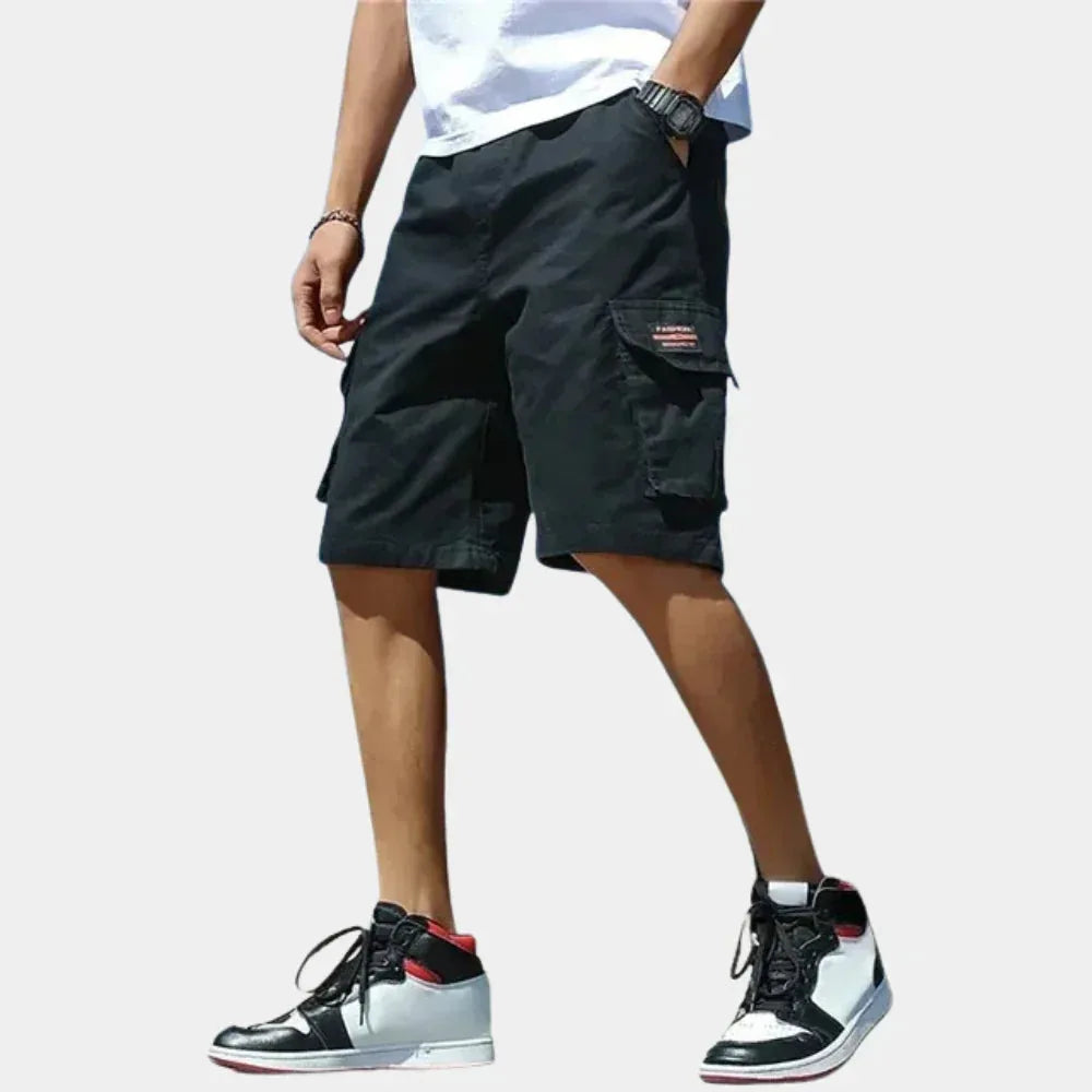 Black cargo shorts paired with a white t-shirt, highlighting the flap pocket and straight hem just above the knee