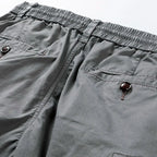 Close-up of grey shorts waistband showing elastic panel, back pocket buttons and stitching detail