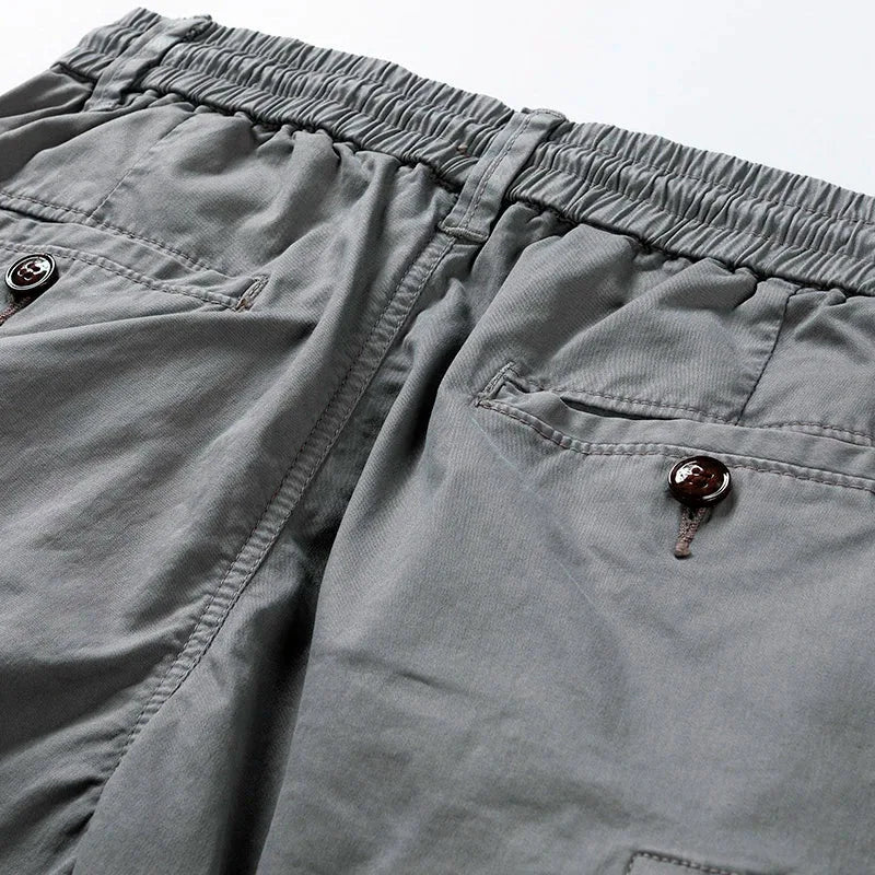 Close-up of grey shorts waistband showing elastic panel, back pocket buttons and stitching detail