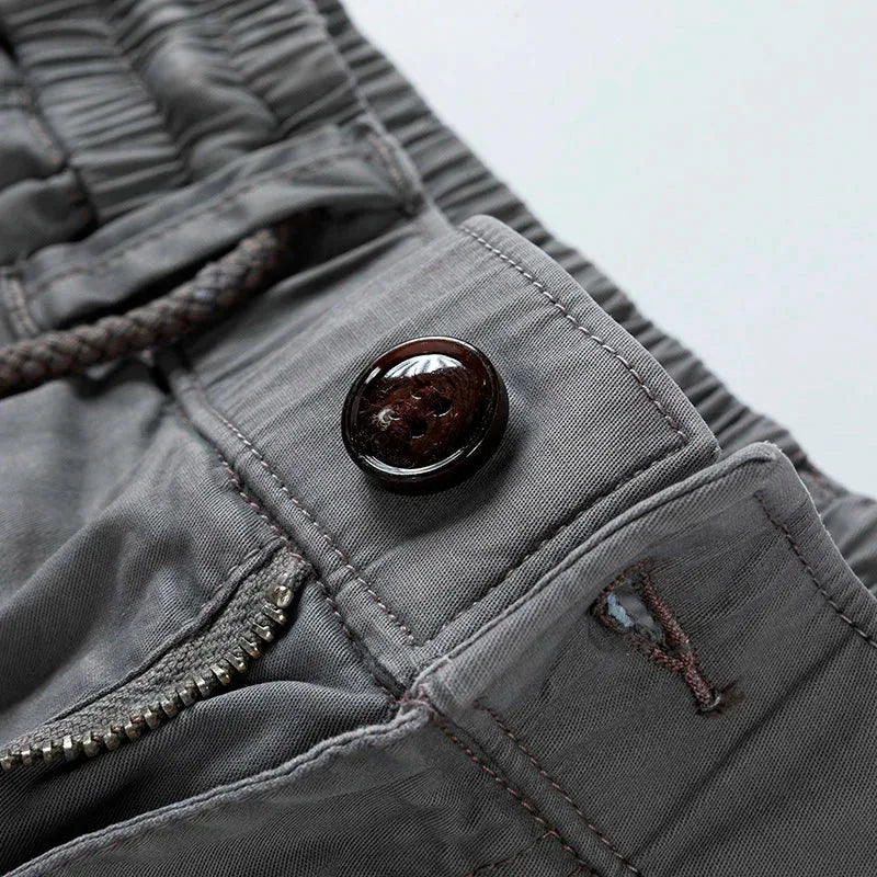 Close-up of grey shorts front button closure with brown button and drawstring cord