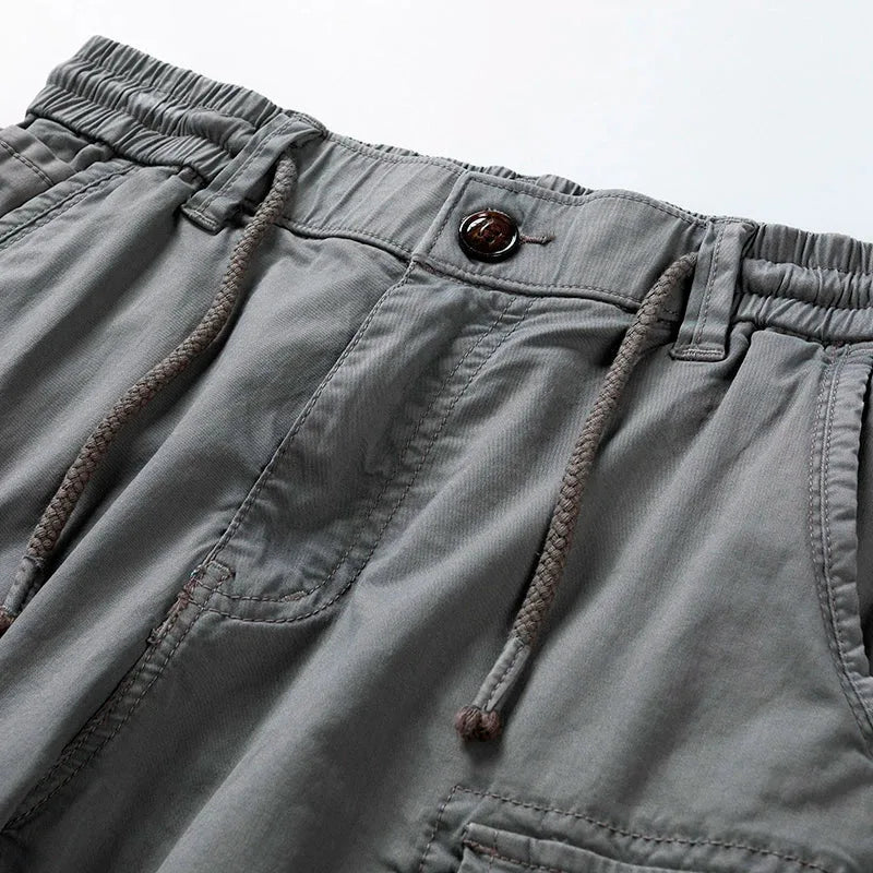Close-up of grey shorts waistband showing drawstring, button tab and cargo pocket stitching