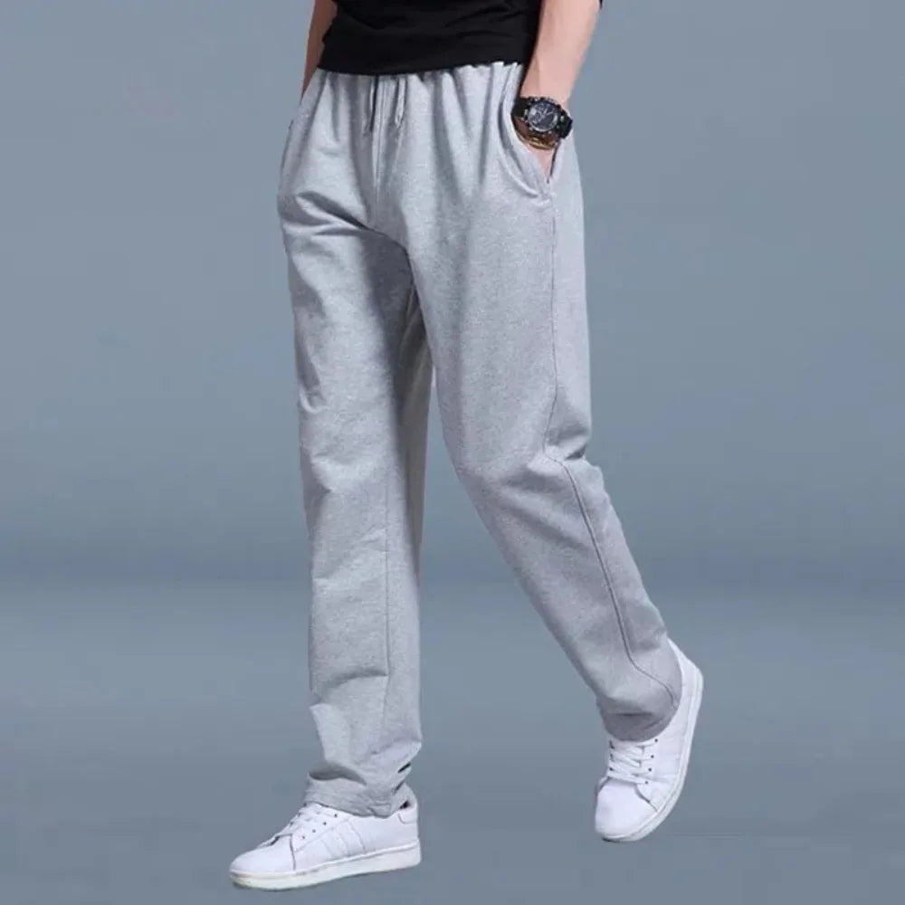 Front view of light grey jogger pants with drawstring waist and side pockets, styled with white sneakers.