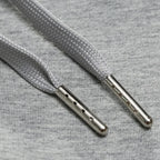 Close-up of the flat grey drawstring cord with metal aglet tips threaded through the waistband.