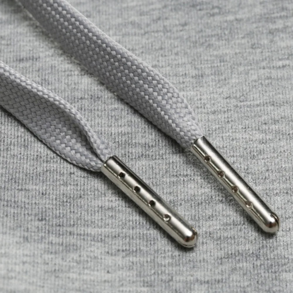 Close-up of the flat grey drawstring cord with metal aglet tips threaded through the waistband.