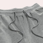 Close-up of the elasticated waistband and adjustable drawstring detail on the grey jogger pants.