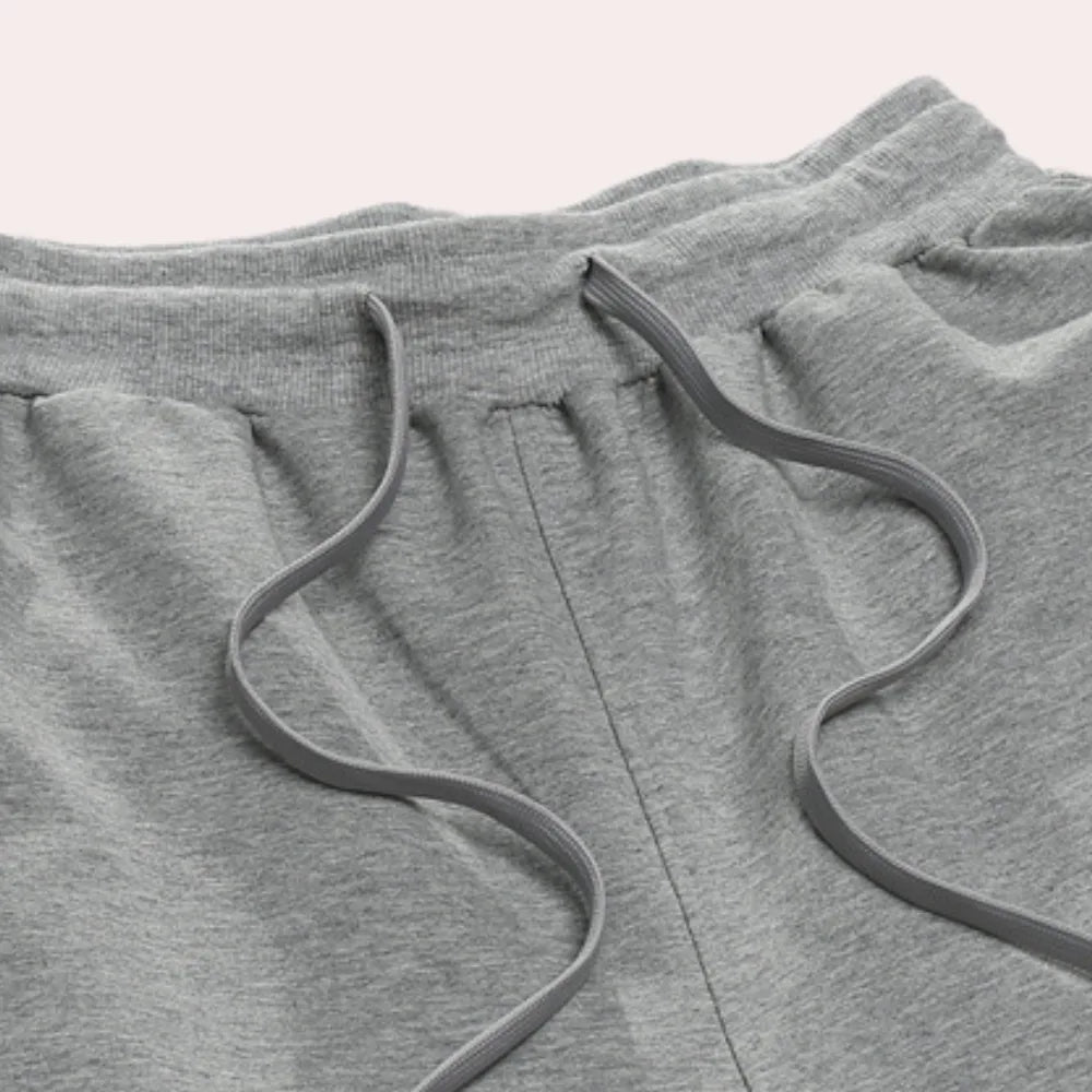 Close-up of the elasticated waistband and adjustable drawstring detail on the grey jogger pants.